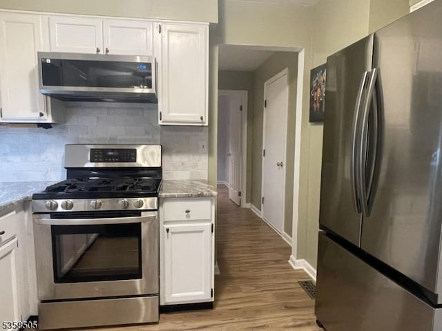 kitchen featuring appliances with stainless steel finishes, white cabinets, and backsplash