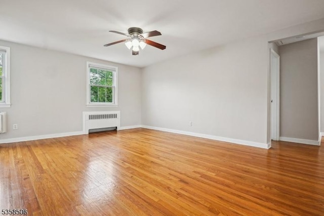 unfurnished living room featuring radiator heating unit, ceiling fan, and light wood finished floors