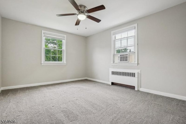 carpeted spare room with radiator, baseboards, a ceiling fan, and cooling unit