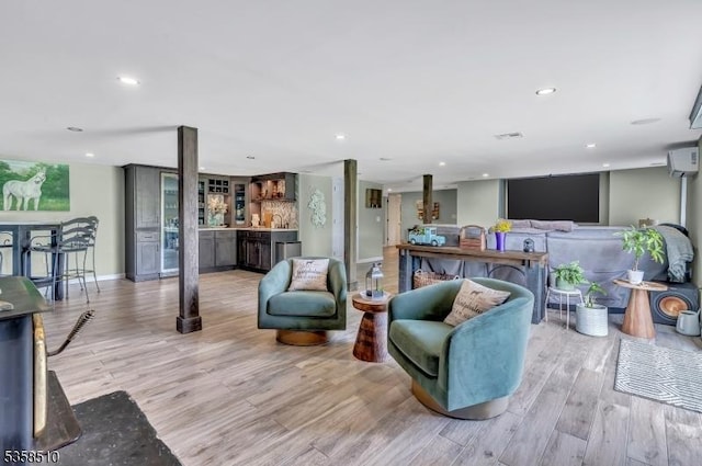 living room with light wood finished floors, a bar, recessed lighting, and baseboards