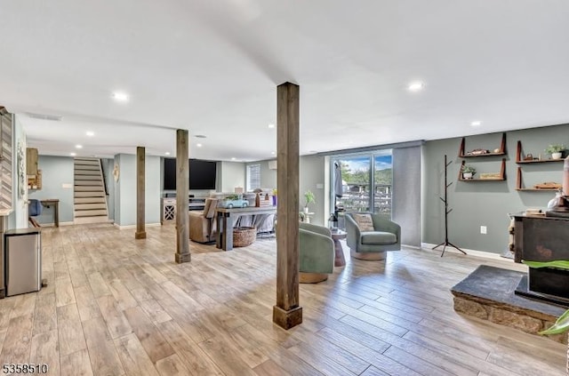 living room with light wood-type flooring, baseboards, recessed lighting, and stairs