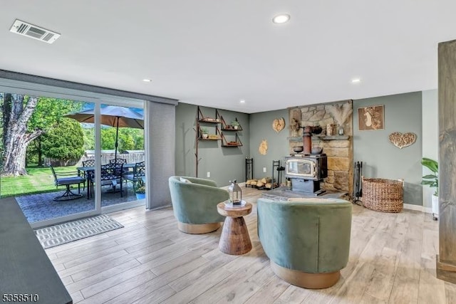 living area with wood finished floors, recessed lighting, a wood stove, and baseboards