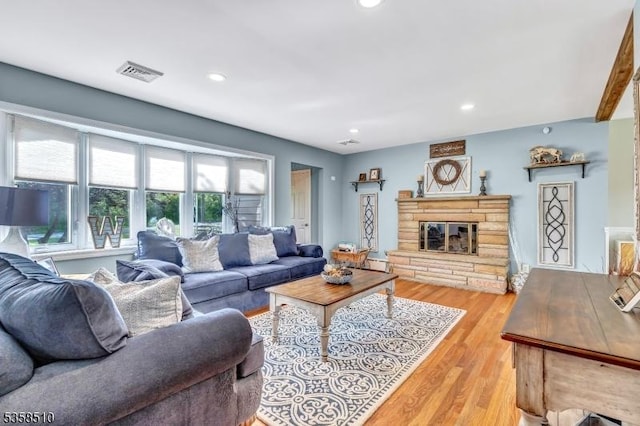 living area featuring recessed lighting, a stone fireplace, and light wood finished floors