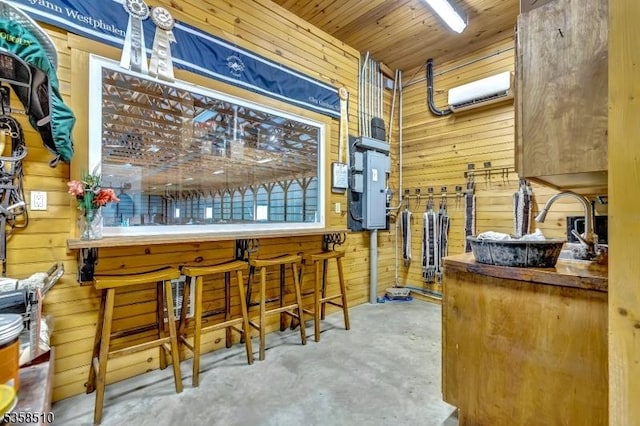 bar area featuring wooden walls and unfinished concrete flooring