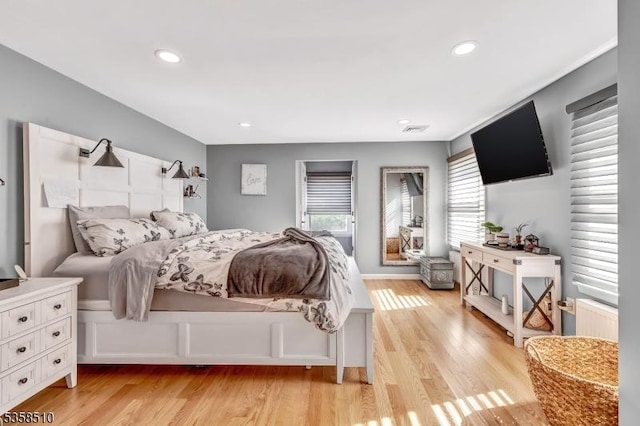 bedroom with light wood finished floors, recessed lighting, and radiator