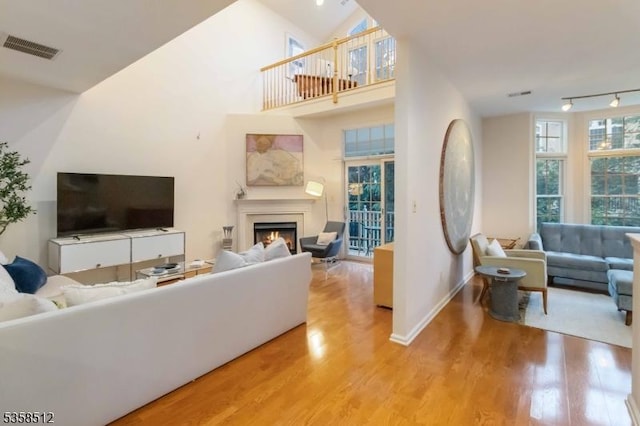 618 Turlington Ct, Livingston Twp, NJ 07039 - living area featuring wood finished floors, a warm lit fireplace, rail lighting, and baseboards
