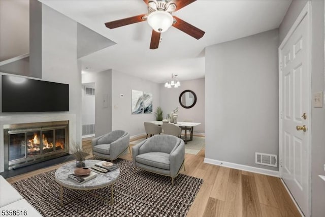 24 Stevens Ct, Bedminster Twp, NJ 07921 - living room with light wood finished floors, a ceiling fan, baseboards, a glass covered fireplace, and a chandelier