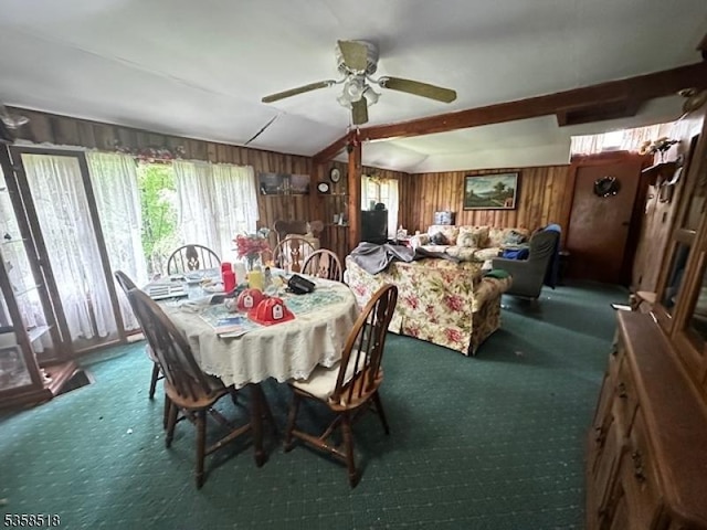 carpeted dining room featuring wooden walls, ceiling fan, and lofted ceiling