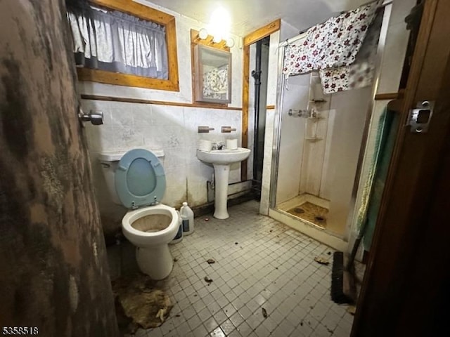 bathroom with a stall shower, toilet, and tile walls