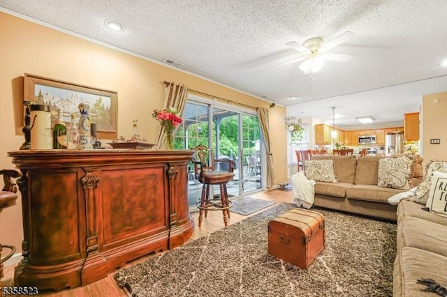 40 Nathan Dr, Old Bridge Twp, NJ 08857 - living room with light wood-style flooring, a textured ceiling, ceiling fan, ornamental molding, and a bar