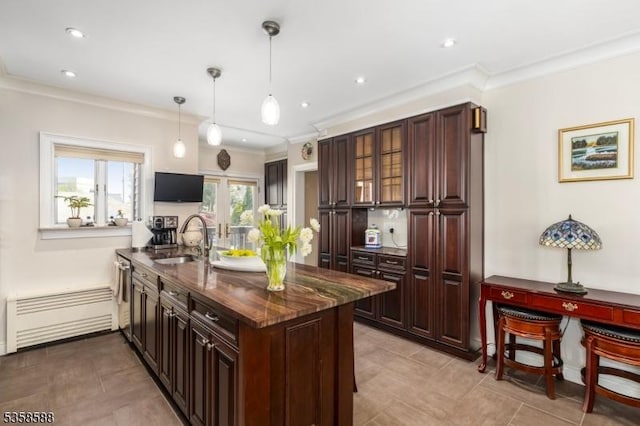 kitchen featuring a sink, radiator heating unit, a peninsula, ornamental molding, and hanging light fixtures
