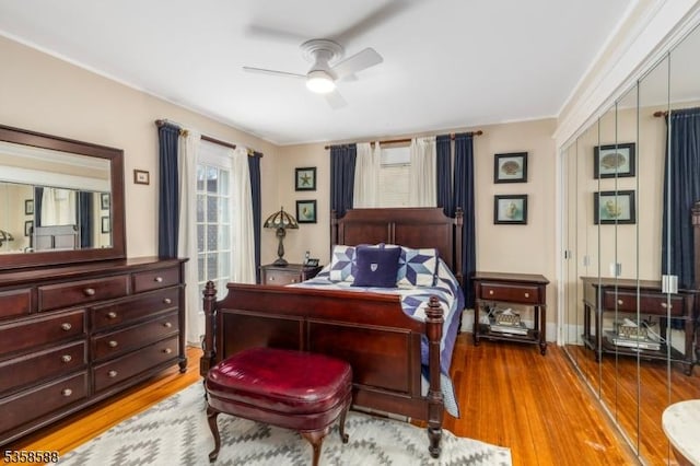 bedroom with wood finished floors, ceiling fan, a closet, baseboards, and ornamental molding