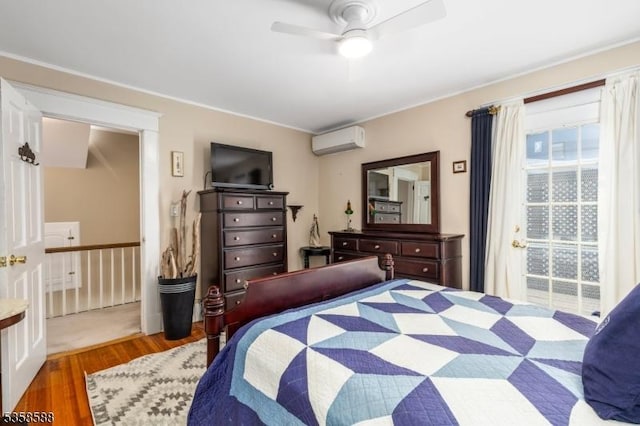 bedroom featuring an AC wall unit, wood finished floors, and a ceiling fan
