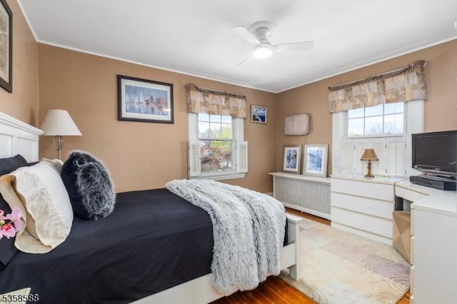 bedroom featuring ornamental molding, wood finished floors, radiator, and ceiling fan