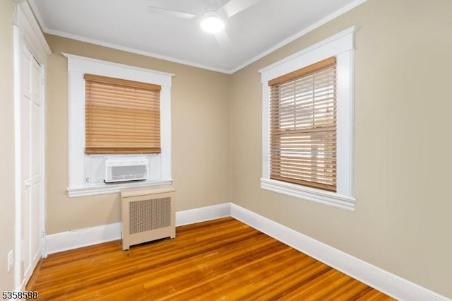 unfurnished bedroom featuring radiator, wood finished floors, cooling unit, baseboards, and crown molding