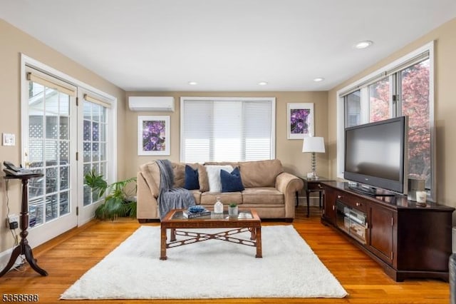 living area with an AC wall unit, light wood-style flooring, and recessed lighting