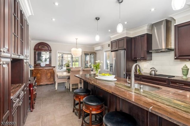 kitchen featuring stainless steel fridge, wall chimney range hood, a sink, a breakfast bar area, and an AC wall unit