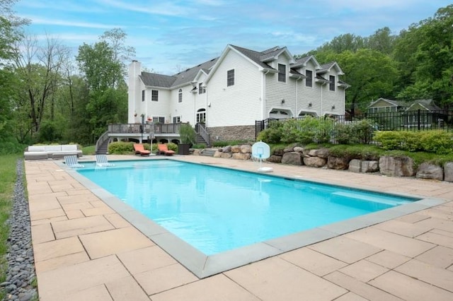 outdoor pool featuring stairs, a wooden deck, a patio, and fence