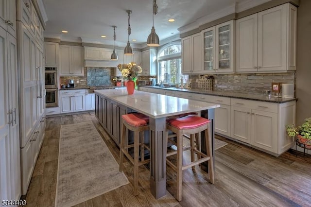 kitchen with appliances with stainless steel finishes, a center island, backsplash, white cabinetry, and crown molding