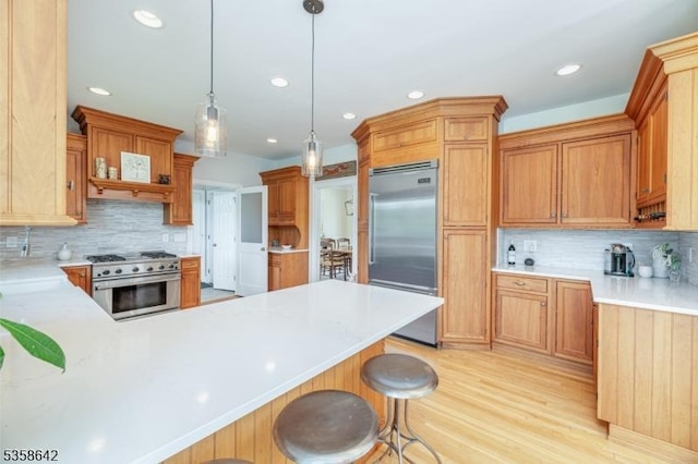 11 Brookside Dr, Peapack Gladstone Boro, NJ 07934 - kitchen with high quality appliances, a peninsula, decorative backsplash, light wood-type flooring, and a breakfast bar area