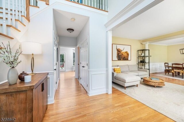 11 Brookside Dr, Peapack Gladstone Boro, NJ 07934 - hallway with light wood-style flooring, a decorative wall, wainscoting, and stairs