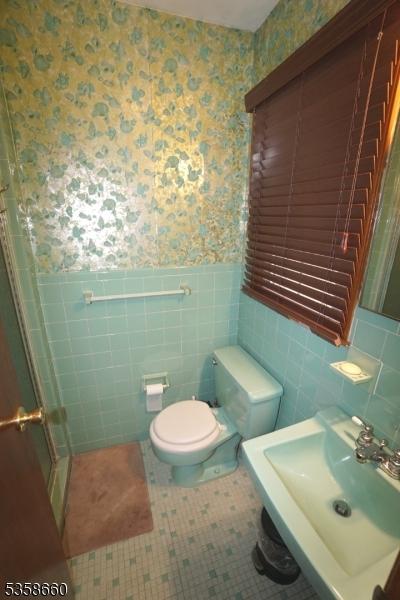 293 Oak Ridge Rd, Clark Twp, NJ 07066 - full bath featuring wallpapered walls, a wainscoted wall, a sink, tile walls, and toilet