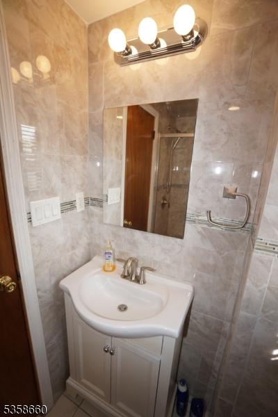 293 Oak Ridge Rd, Clark Twp, NJ 07066 - bathroom featuring tile walls, vanity, and a tile shower