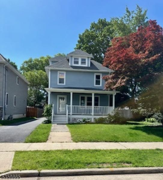 american foursquare style home featuring covered porch and a front lawn