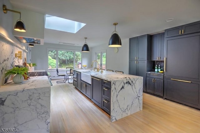25 Highland Ave, Peapack Gladstone Boro, NJ 07931 - kitchen featuring a sink, a skylight, light wood-style flooring, light stone countertops, and pendant lighting