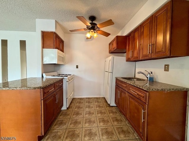 kitchen with white appliances, a sink, a ceiling fan, a textured ceiling, and dark stone counters