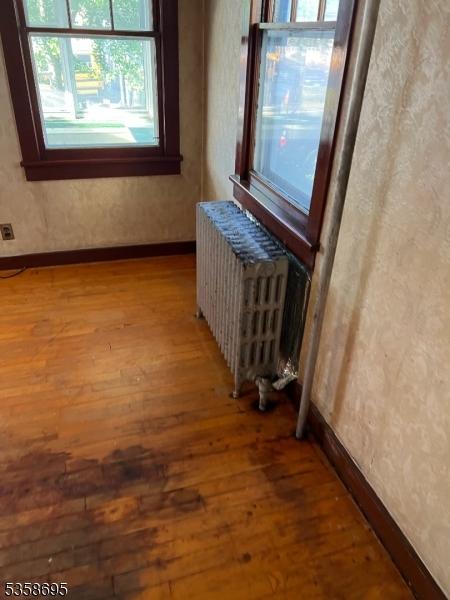 626 Tremont Ave, City Of Orange Twp, NJ 07050 - hallway featuring radiator heating unit, wood finished floors, healthy amount of natural light, and baseboards