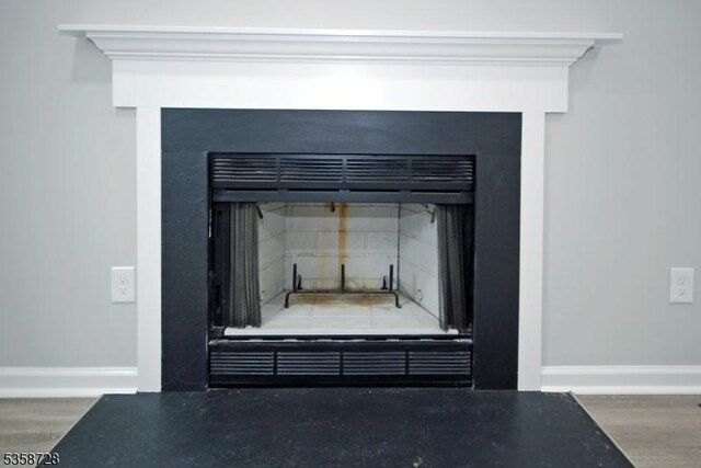 detailed view of a fireplace with flush hearth, baseboards, and wood finished floors