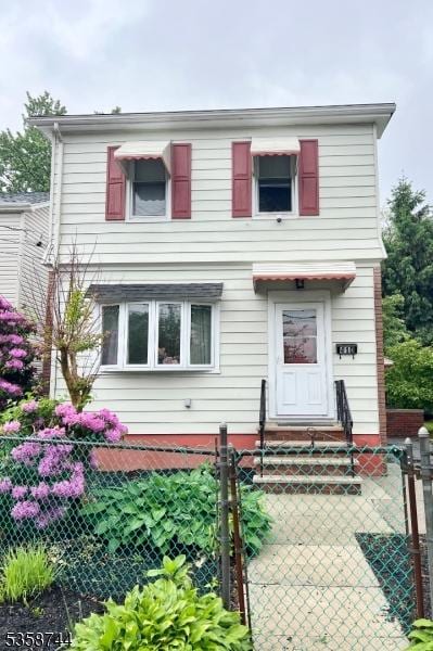 traditional home featuring a fenced front yard and a gate