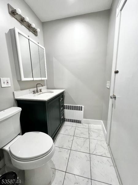 bathroom featuring radiator, marble finish flooring, toilet, and vanity