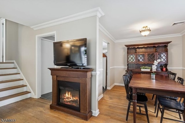457 Valley Rd, Long Hill Twp, NJ 07933 - dining room with light wood-style flooring, crown molding, a glass covered fireplace, and stairway