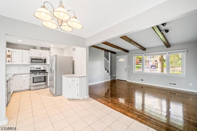 132 Hiawatha Blvd, Oakland Boro, NJ 07436 - kitchen featuring stainless steel appliances, a chandelier, beamed ceiling, light countertops, and white cabinetry