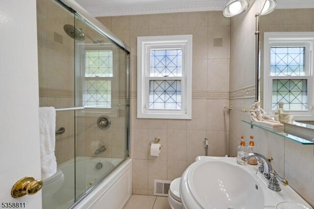 21-23 Sheridan Ave, West Orange Twp, NJ 07052 - bathroom featuring a sink, plenty of natural light, ornamental molding, combined bath / shower with glass door, and tile walls