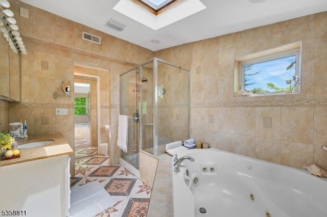 21-23 Sheridan Ave, West Orange Twp, NJ 07052 - bathroom with tile walls, a skylight, a stall shower, a whirlpool tub, and vanity