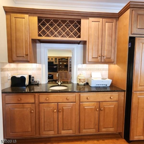 15 Hemlock Ave, Frankford Twp, NJ 07826 - kitchen with a sink, dark stone countertops, backsplash, brown cabinetry, and crown molding