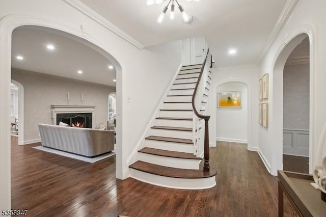47 Barnsdale Rd, Millburn Twp, NJ 07078 - stairs with wood finished floors, arched walkways, ornamental molding, a lit fireplace, and a chandelier
