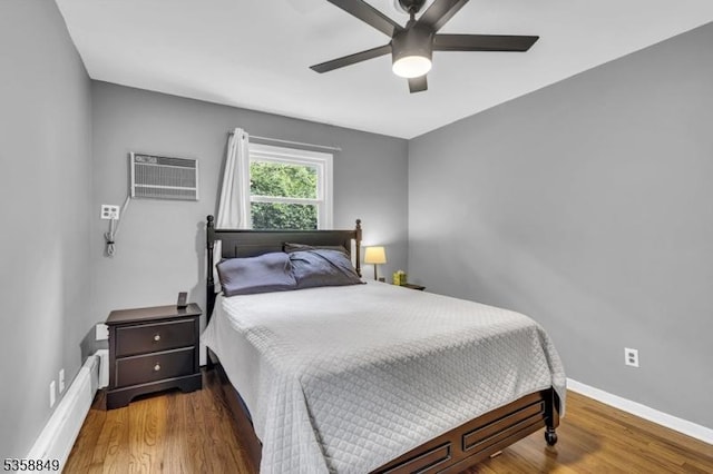 bedroom with a wall mounted AC, wood finished floors, baseboards, and ceiling fan