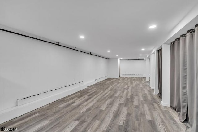 finished basement with baseboard heating, wood finished floors, recessed lighting, and baseboards