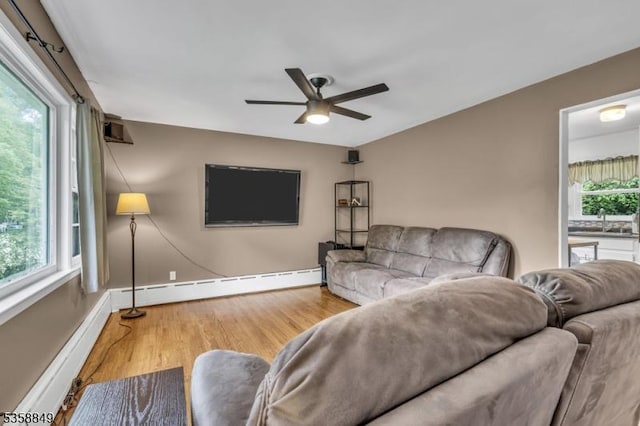 living room featuring a baseboard heating unit, a ceiling fan, wood finished floors, and baseboards