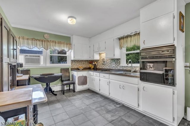 kitchen with black oven, a sink, decorative backsplash, cooling unit, and white cabinets