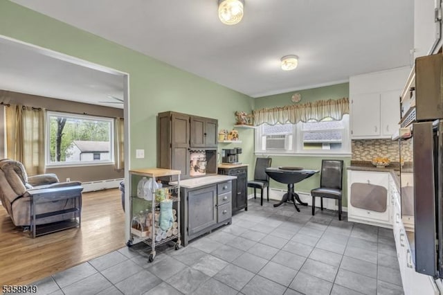 kitchen featuring decorative backsplash, baseboard heating, and light tile patterned floors