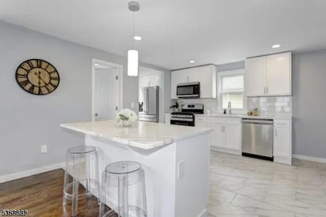 39 Emma St, Plainfield City, NJ 07063 - kitchen featuring appliances with stainless steel finishes, white cabinets, a breakfast bar, decorative light fixtures, and baseboards