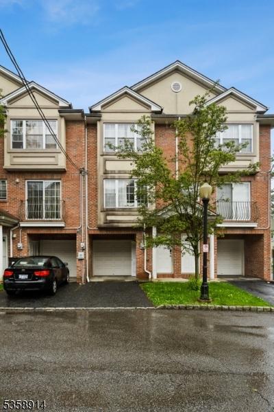 multi unit property featuring driveway, an attached garage, and brick siding