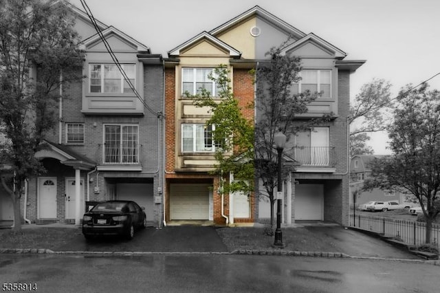 townhome / multi-family property with driveway, brick siding, and a garage