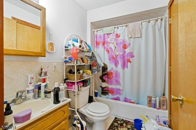 full bath featuring toilet, shower / bath combo with shower curtain, vanity, tile patterned floors, and tile walls