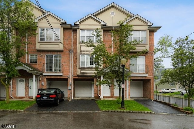 townhome / multi-family property with driveway, an attached garage, and brick siding
